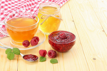 healthy background. raspberry with raspberry jam, honey and tea on light wooden background.