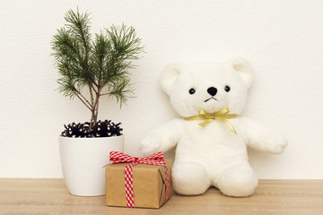 Concept of interior decor. White bear toy for baby, gift box, fir tree in white pot