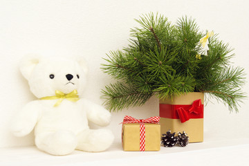 Concept of interior decor. White bear toy for baby, gift box, fir tree in vase