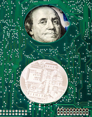 Silver bitcoin lying over electronic circuit board with american dollars