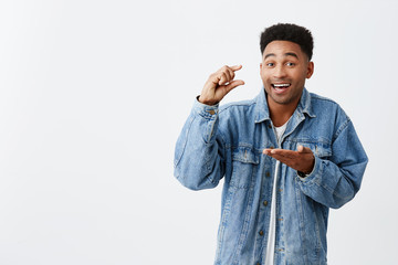 Little. Tiny. Isolated portrait of young good-looking funny happy black-skinned man with afro...