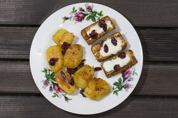 Roasted tofu with garlic sauce and cranberries, baked potatoes. Top view. Wooden rustic background