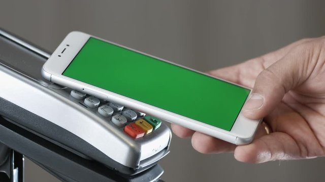 Close-up view of person using contactless payment with nfc techology. Smartphone with green screen template
