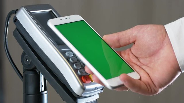 Close-up view of person using contactless payment with nfc techology. Smartphone with green screen template