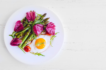 Fried egg and roasted fresh asparagus in black plate