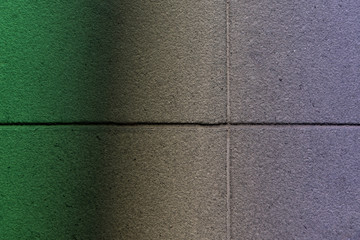 Fototapeta premium Сoncrete tiles illuminated by the transition from green light to violet. Abstract colorful texture background
