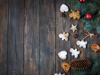 Christmas gingerbread cookies and fir tree and cones on dark stone background. Top view and copy space
