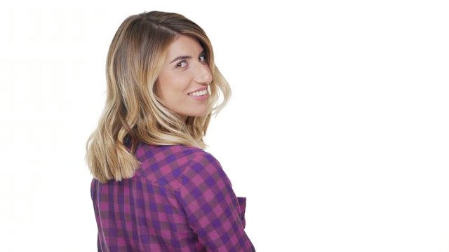 portrait from back of cute young woman with dyed blond hair turning around looking at camera smiling with white teeth being joyful over background copy space. Concept of emotions