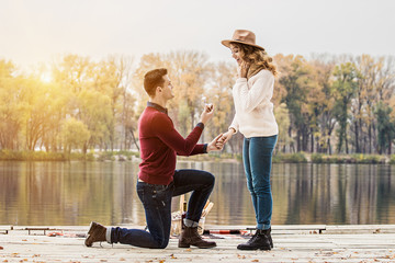 Marry me. Horizontal shot of young man in casual clothing standing on one knee and holding...