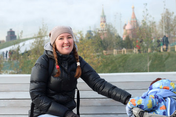 Mother with a child sitting on a Park bench near red square