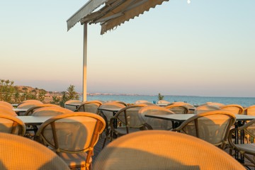 Fototapeta premium chairs and tables on a beach restaurant during sunset