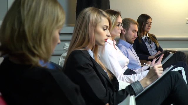 Employees sit on the pouf during a presentation and write in notebooks, refocus shooting