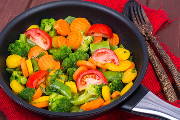 Carrots, broccoli, tomatoes  in  frying pan. Vegetarian menu