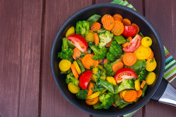 Carrots, broccoli, tomatoes  in  frying pan. Vegetarian menu