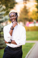 Portrait of young handsome afro american man with blonde hair walking in the sunny city streets.