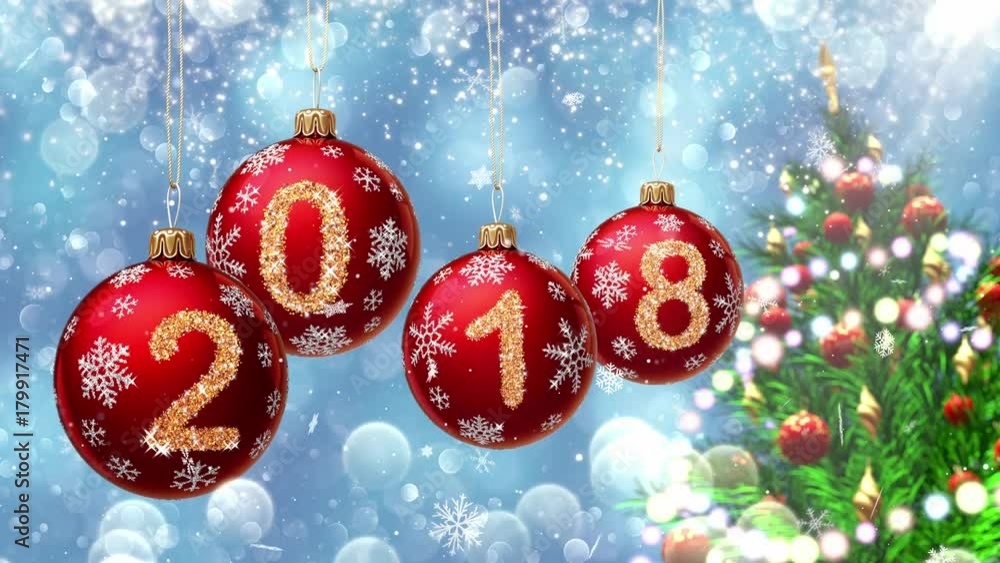 Wall mural red balls with numbers 2018 hanging on the background of a blue bokeh and a rotating christmas tree 
