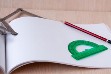 Green protractor and pencil on open page of the album