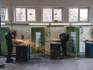 Mechaniker schleifen Stahl in der Werkstatt, viele Funken fliegen durch die Halle