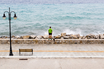 Runner on city street looking at inspiring sea view