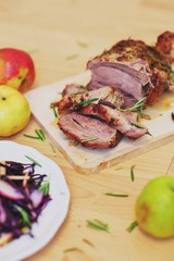 Tasty flavored meat large slices on Wooden chopping Board with spices sides.Vegetable salad made of red cabbage and radish the plate. Apples a table. Macro, selective focus.