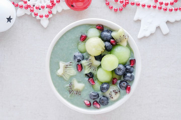 Blue spirulina smoothie bowl with melon, kiwi fruit, pomegranate and blueberries, christmas fun food