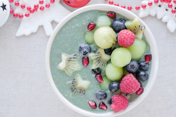Blue spirulina smoothie bowl with melon, kiwi fruit, raspberries and blueberries, christmas fun food