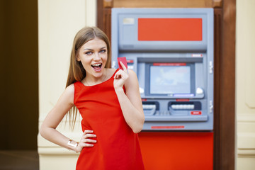 Fototapeta na wymiar Happy blonde woman withdrawing money from credit card at ATM