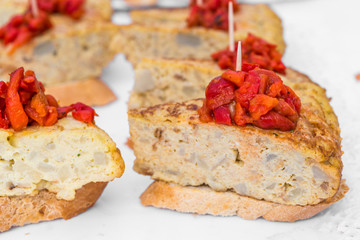 Close up of a tapa with bread, Spanish tortilla omelette, and vegetables