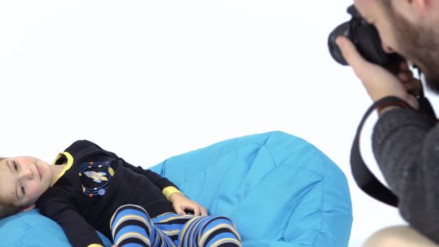 Little boy in pajamas posing for photographer at white background