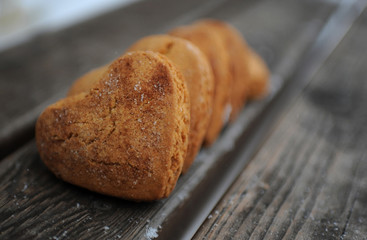 Homemade cookies with sugar and cinnamon in the form of hearts on a wooden background
