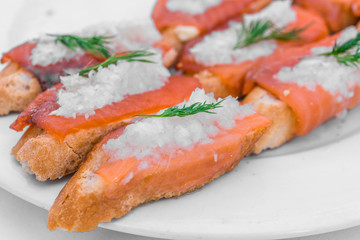 Close up of a tapa with bread, smoked salmon, marinated onion, and dill at a street food market