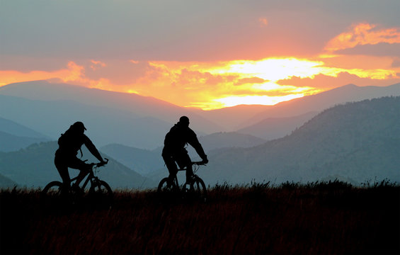 Mountain bikers on a trail at sunset