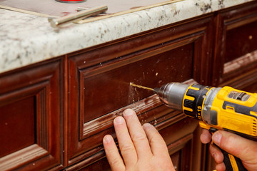 master drills the door in the cabinet door