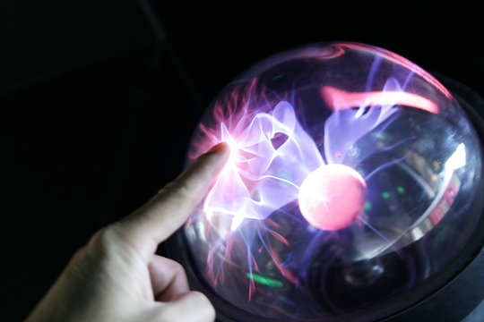 hand touching plasma globe
