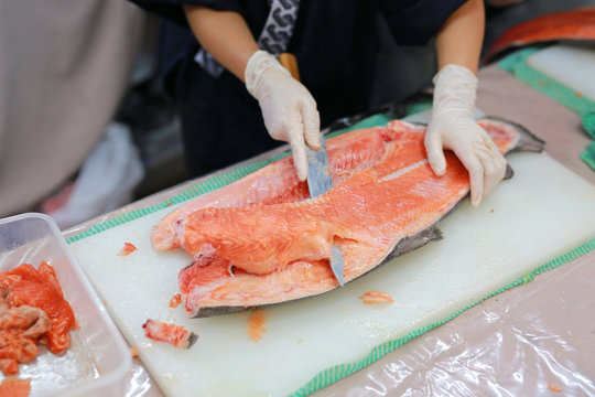 The chef cuts the salmon on the table.