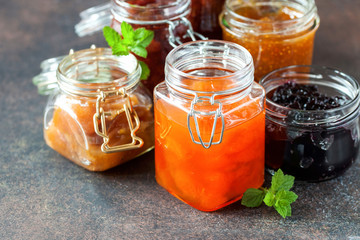 Various jars of fruit jam on dark table. Selective focus