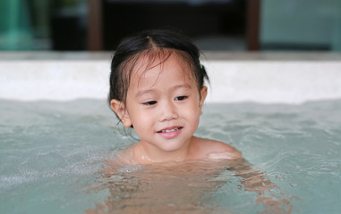 Fototapeta na wymiar Happy little Asian girl lying in the hot tub.