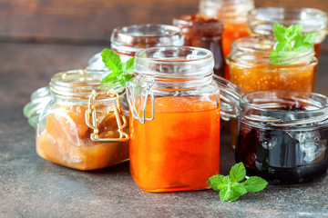 Various jars of fruit jam on dark table. Selective focus