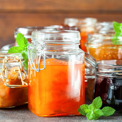 Various jars of fruit jam on dark table. Selective focus