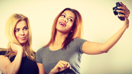 Two models girls taking self picture with camera
