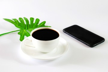 Obraz na płótnie Canvas Flat lay photo with Black Coffee, Cellphone and Tropical Leaf isolated on white background