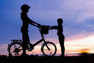 Fototapeta na wymiar Silhouettes of biker family on the beach at beautiful sunset.family and teamwork concept.