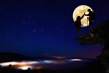 Teamwork hiking help each other trust assistance at mountains and beautiful full moon,teamwork and hiking concept.