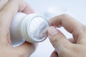 Hands opening foil  protective sealed on top of white plastic bottle for protection pills from broken keep product in good quality.