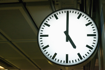 Classic analog clock pointing at 5 o'clock with dark background
