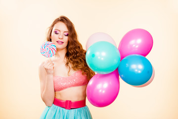 Woman holds lollipop candy and balloons