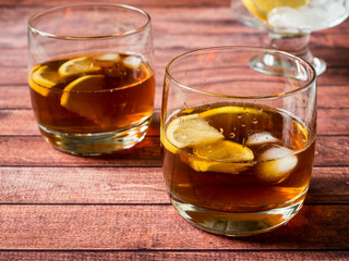 Glasses of cocktail with ice and lemon on wooden table close-up