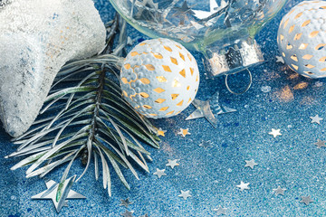fir tree branch, christmas tree lights and decorations on blue sparkling background macro view