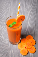 Carrot smoothie with ingredients on wooden background
