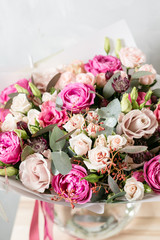 beautiful bouquet of mixed flowers into a vase on wooden table